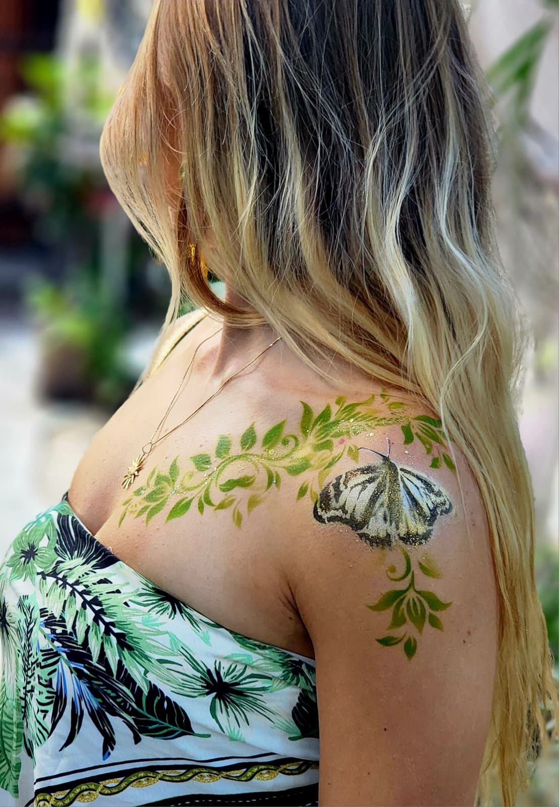 Trailing green vine and painted butterfly across the shoulder and upper arm